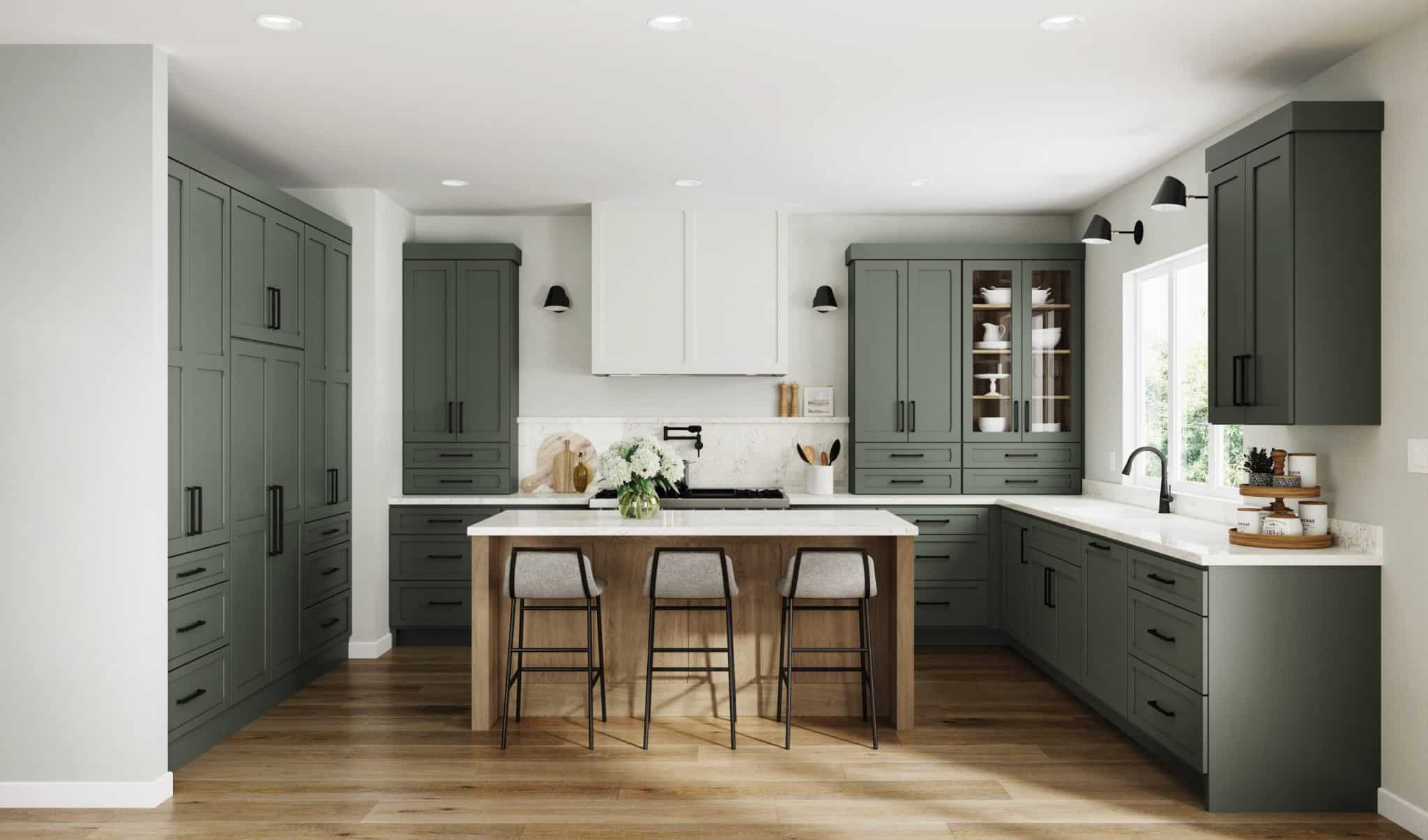 Tall white chimney-style range hood centered over a cooktop between green wall cabinets in a remodeled kitchen