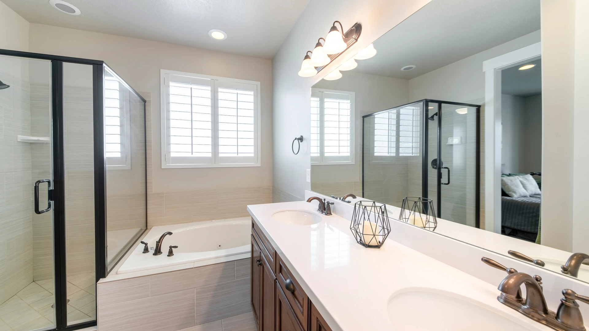 Bathroom double vanity with two undermount sinks and a long mirror, beside a glass-enclosed shower and a drop-in tub