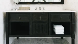 Black furniture-style bathroom vanity with a light countertop, open shelves and folded white towels
