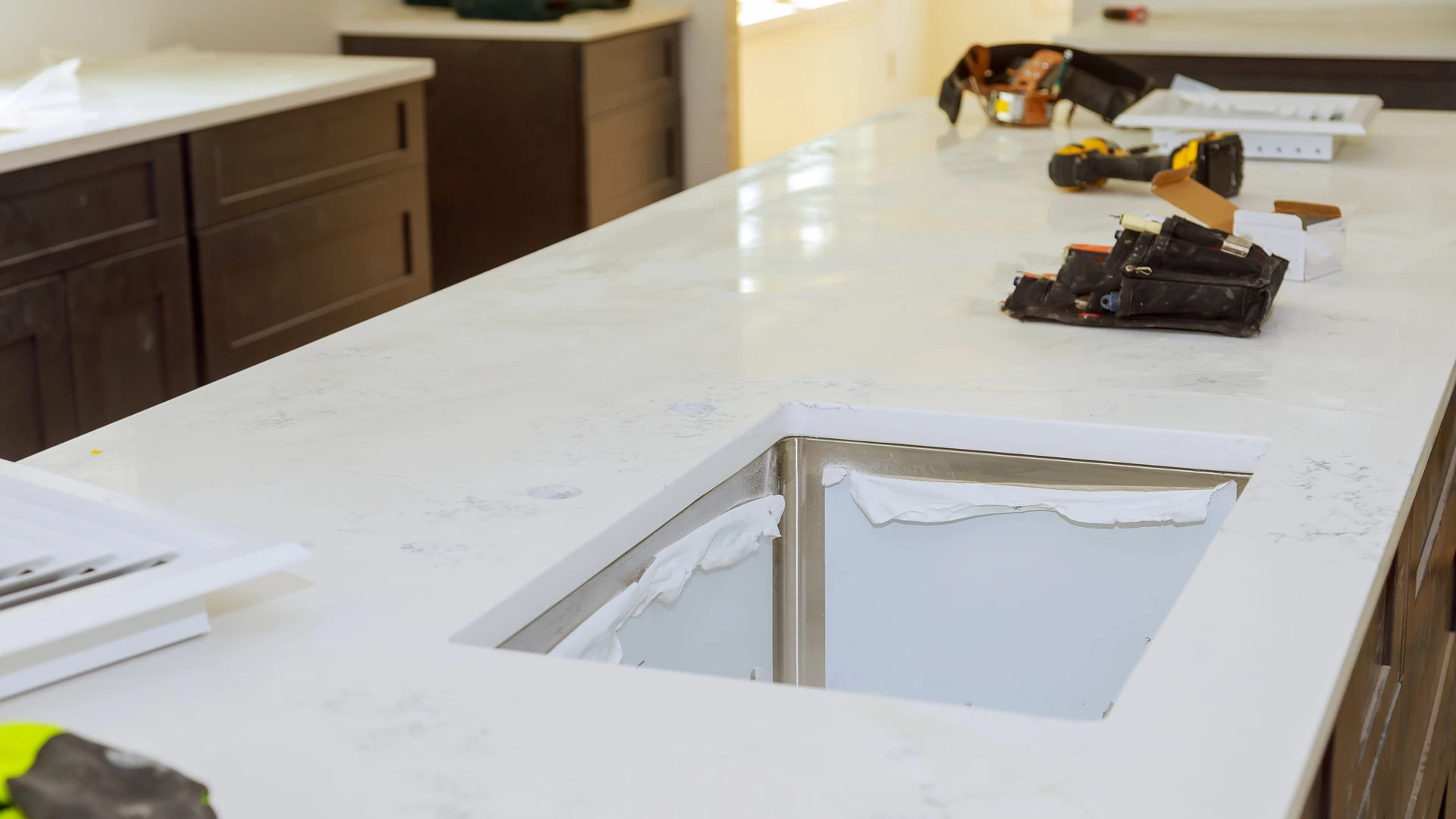 Pale veined countertop with an open sink cutout and tools on the surface