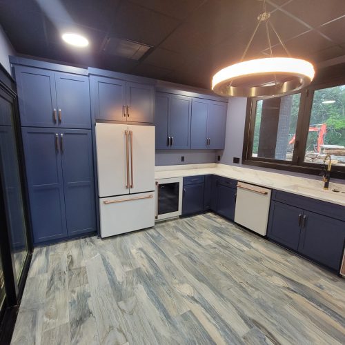 Blue kitchen cabinets with white appliances and a glowing ring pendant
