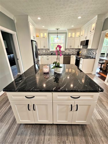 Completed white kitchen with black stone island and custom cabinetry by Guthrie Kitchen & Bath