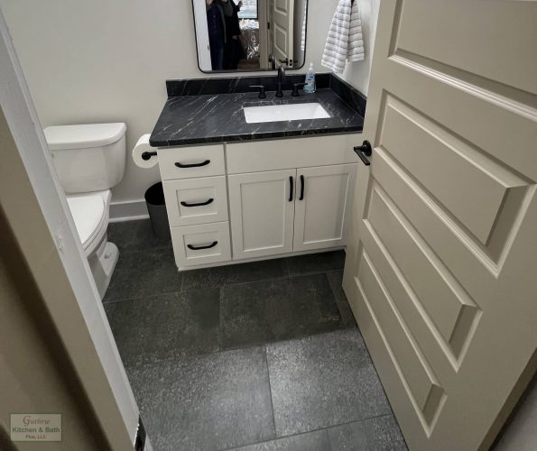 Completed powder room with custom vanity and dark stone countertop by Guthrie Kitchen & Bath